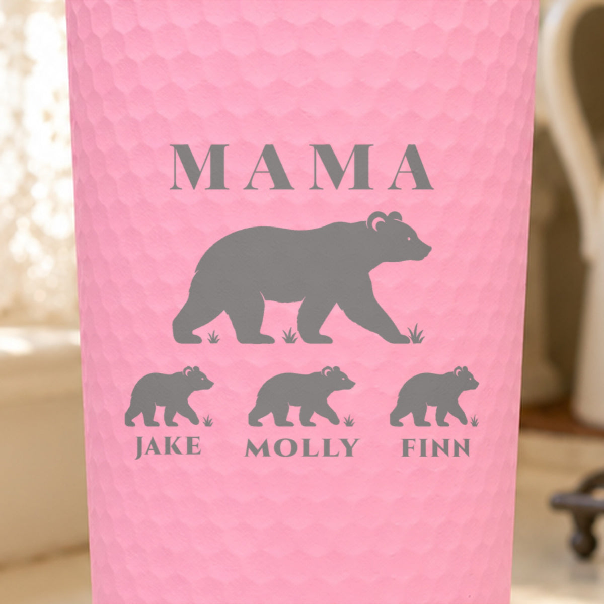 Close-up of the laser engraving on a pink dimpled tumbler: MAMA, a mama bear and three cubs named Jake, Molly and Finn