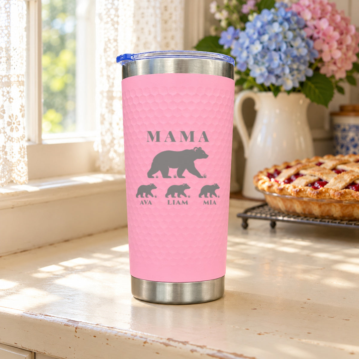 Pink textured tumbler engraved MAMA with a mama bear and three named cubs, Ava, Liam and Mia, a personalized gift for mom in a kitchen