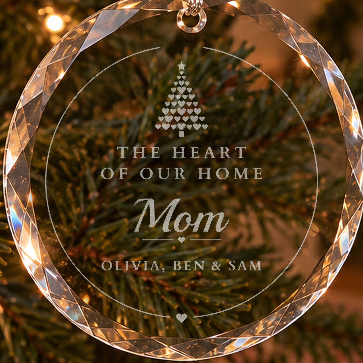 Close-up of the frosted engraving on a personalized mom Christmas ornament: a tree of hearts above The Heart of Our Home, Mom and Olivia, Ben and Sam