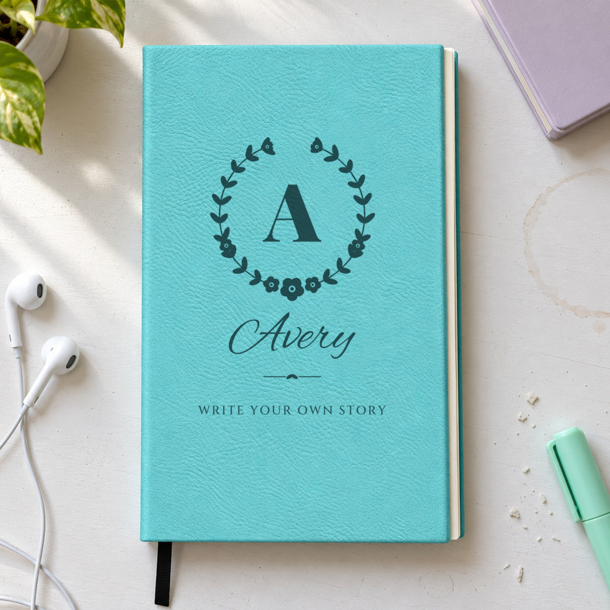 Monogram journal for her in teal, engraved with the initial A in a wildflower wreath, Avery in script and Write Your Own Story below