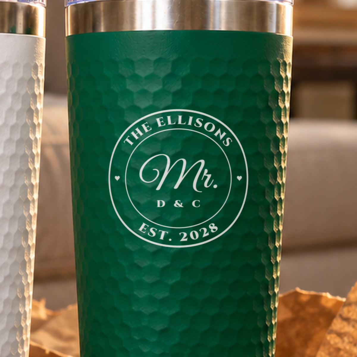 Close-up of the laser engraving on a green tumbler: a round seal with The Ellisons, Mr., D & C and Est. 2028 in light silver
