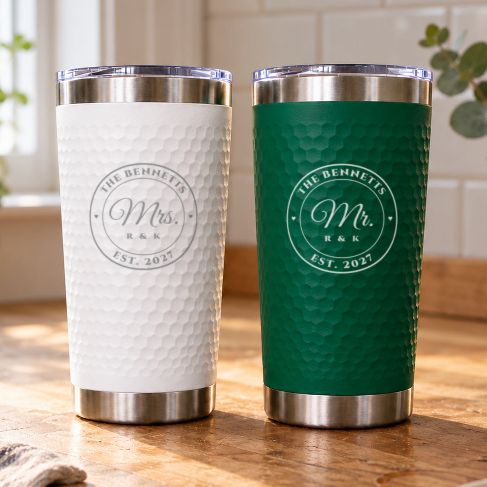 Green and white Mr. and Mrs. tumbler set engraved with a round seal reading The Bennetts, Est. 2027, on a sunny kitchen counter