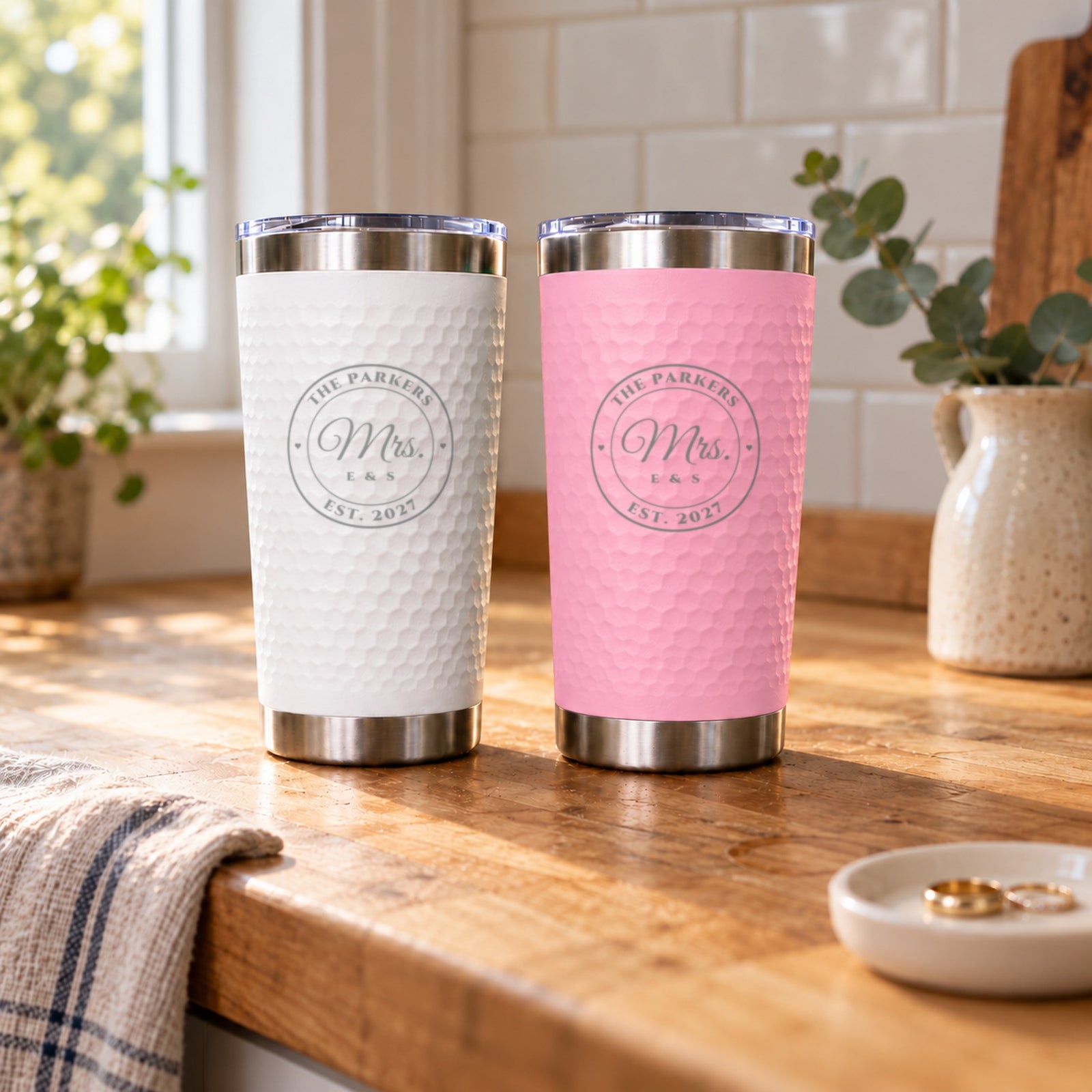 White and soft pink engraved tumblers reading Mrs. and Mrs. for The Parkers, Est. 2027, on a kitchen counter, a wedding gift for two brides