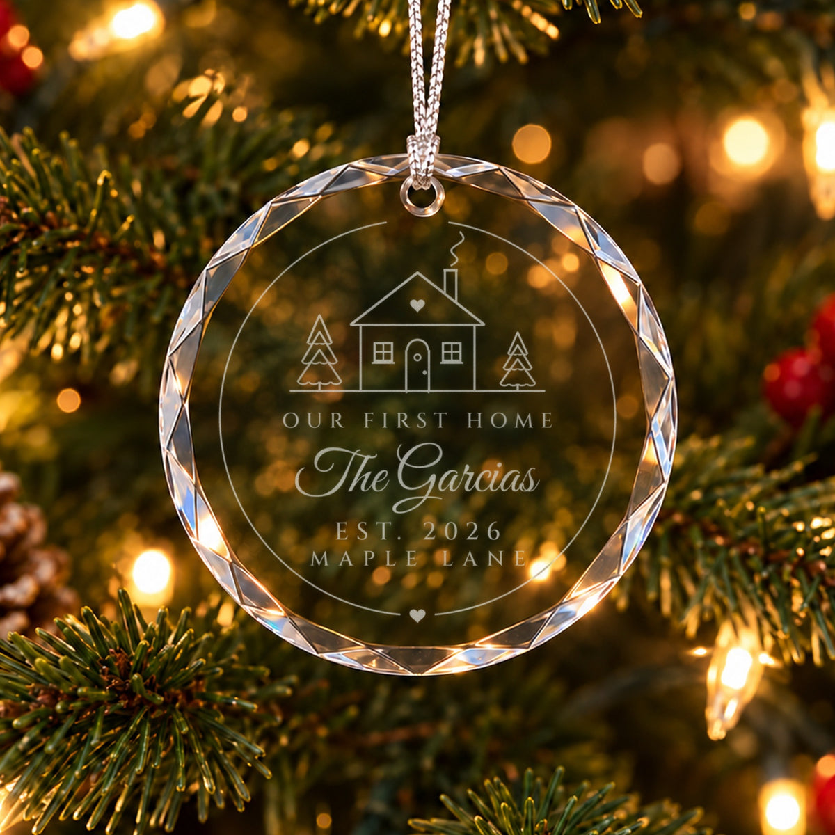 Personalized first home ornament in faceted glass on a Christmas tree, engraved with a cottage, OUR FIRST HOME, The Garcias, EST. 2026 and Maple Lane