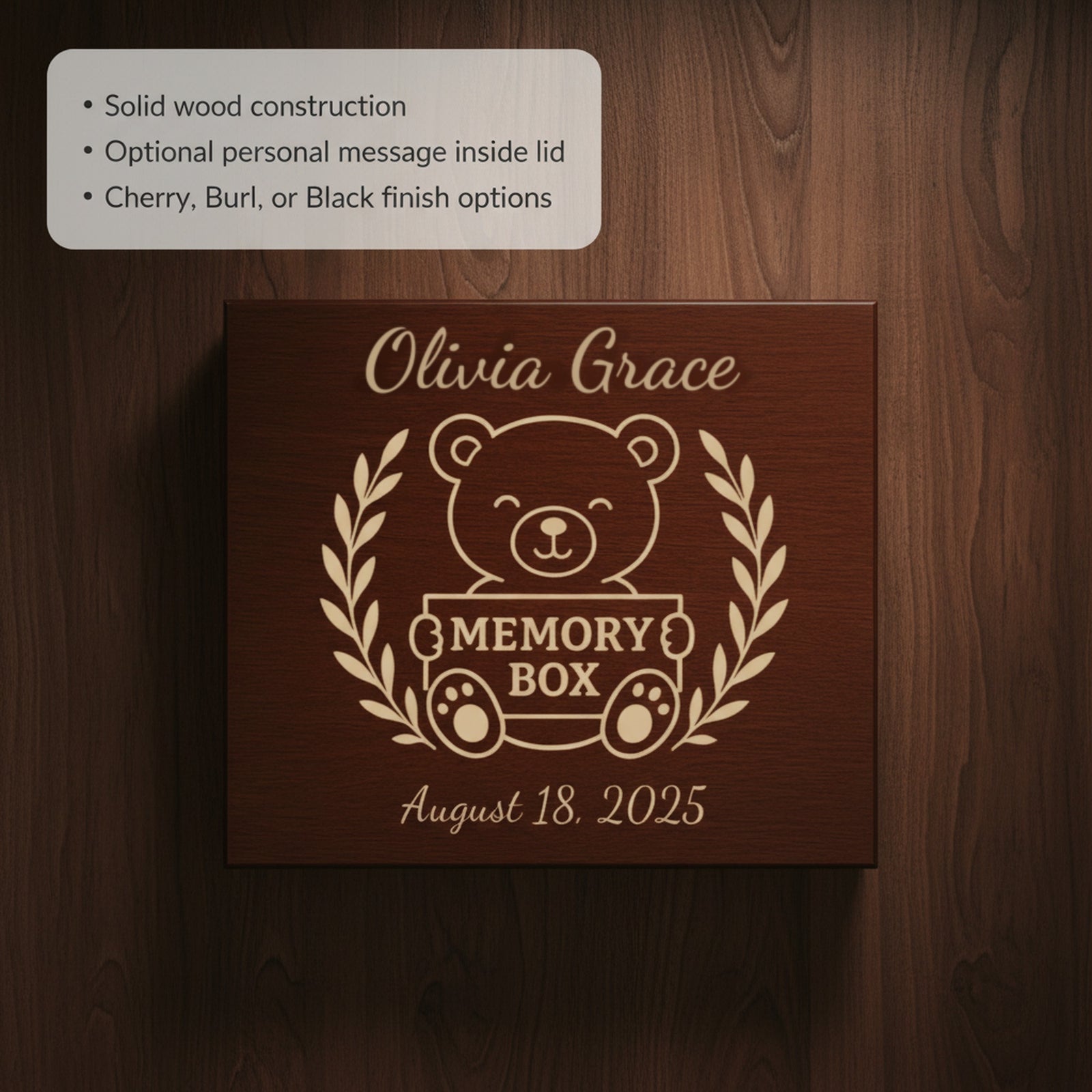 Close view of the engraved teddy bear baby memory box lid holding a Memory Box sign, with a sample name above and a birth date below the laurel wreath