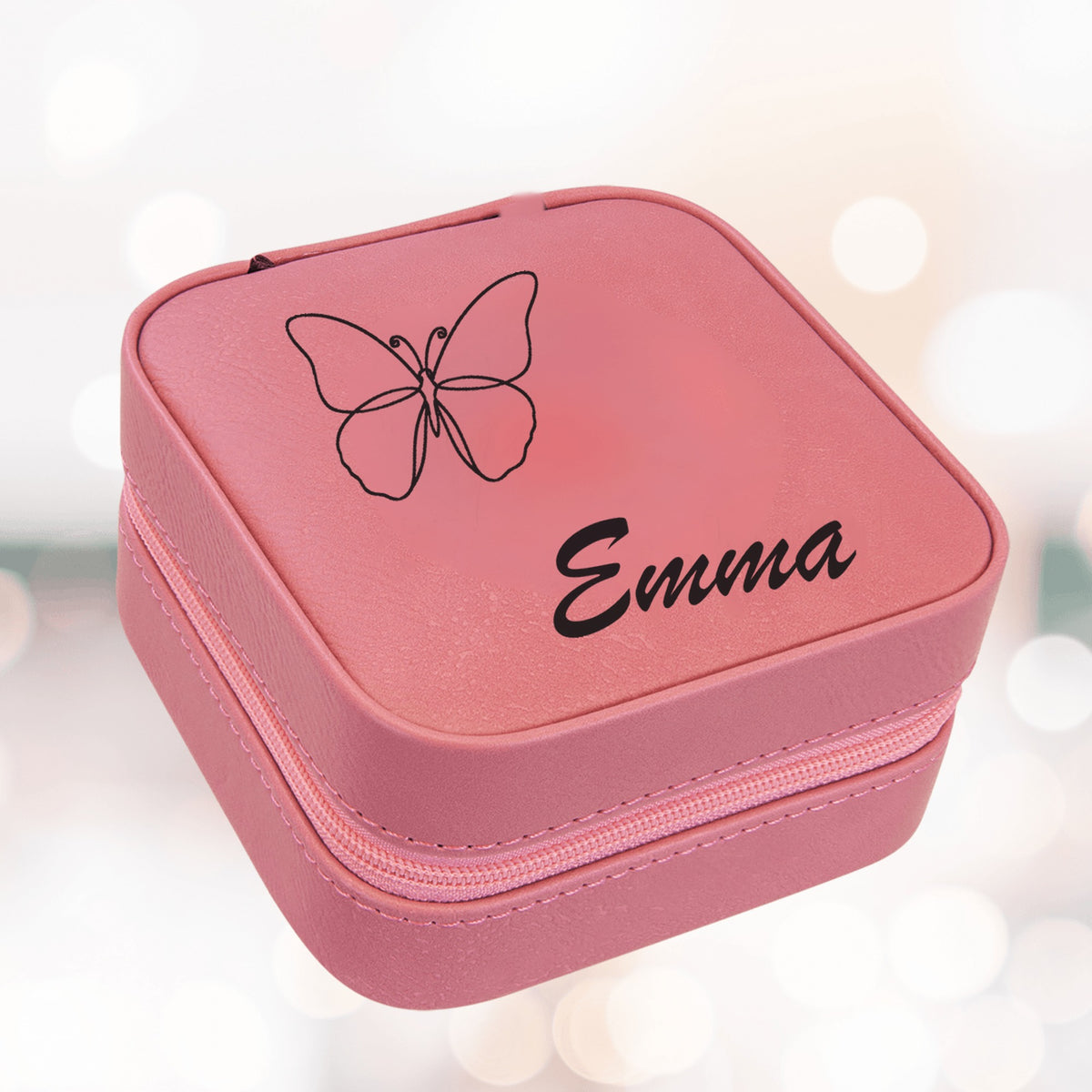 Pink personalized jewelry box for girls engraved with a fine-line butterfly and the sample name Emma in script across the zippered leatherette lid