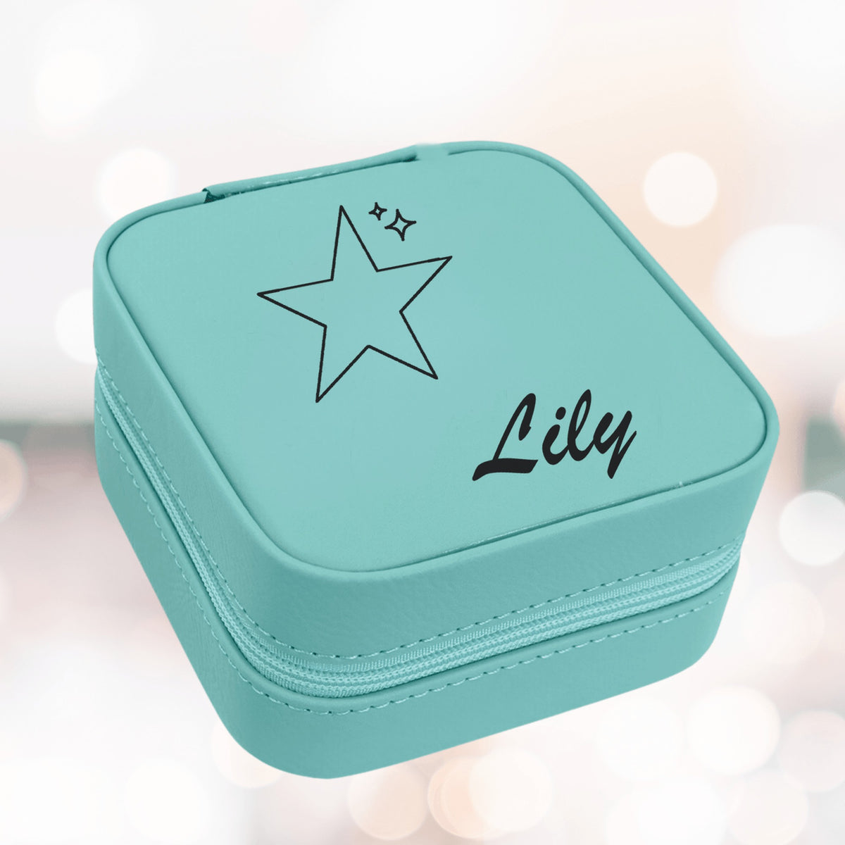 Teal kids jewelry box with a laser engraved star, two small sparkles and the sample name Lily in script on the lid of the zippered case