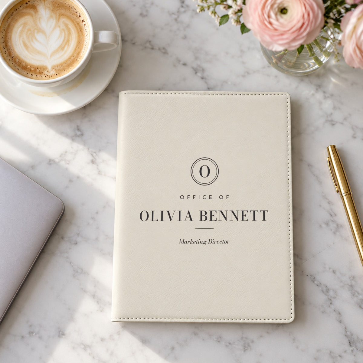 Personalized padfolio for women in white, engraved with an O seal, Office of, Olivia Bennett and Marketing Director, on a marble desk beside a latte