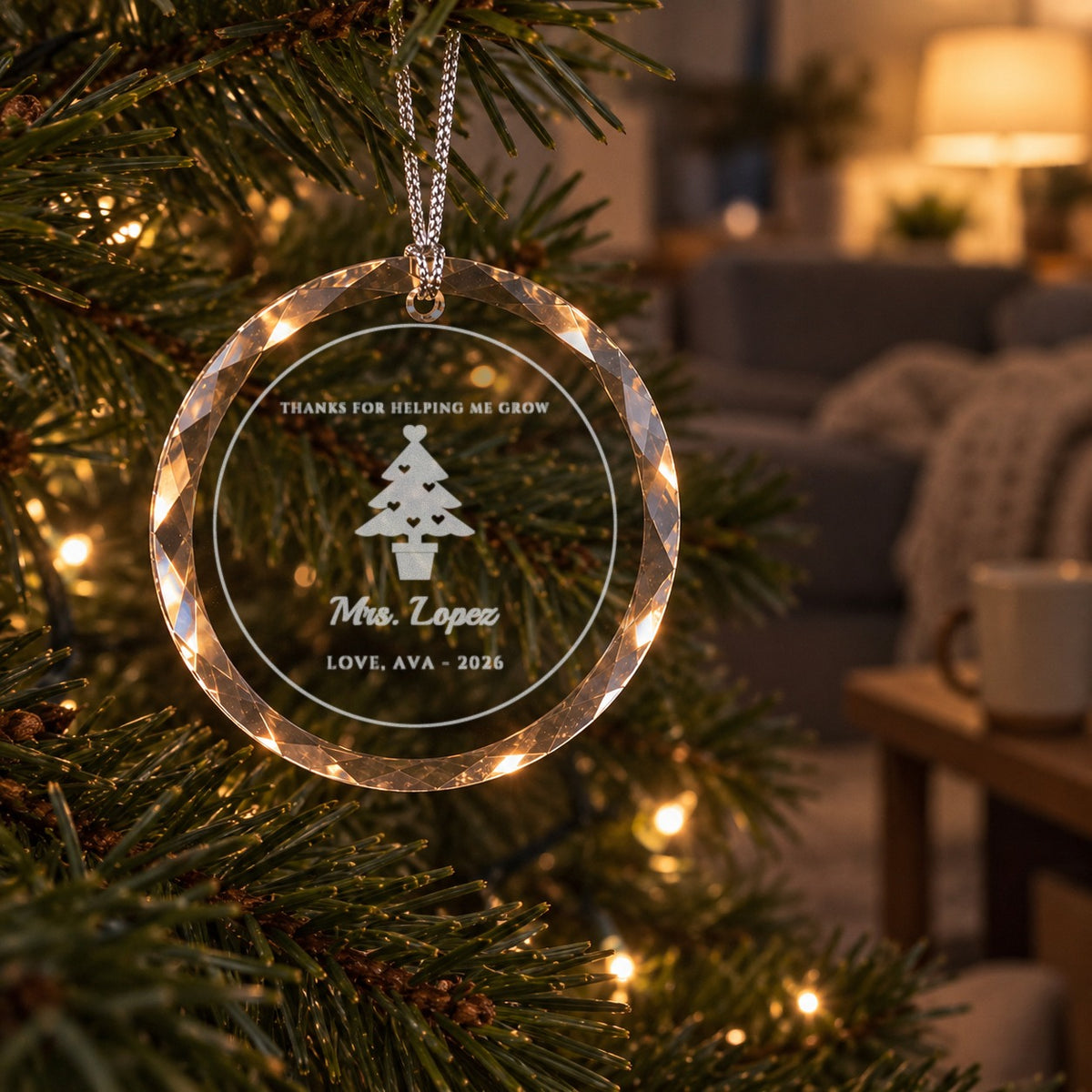 Personalized teacher Christmas ornament in clear faceted glass on a lit tree at home, engraved THANKS FOR HELPING ME GROW, a heart tree and Mrs. Lopez
