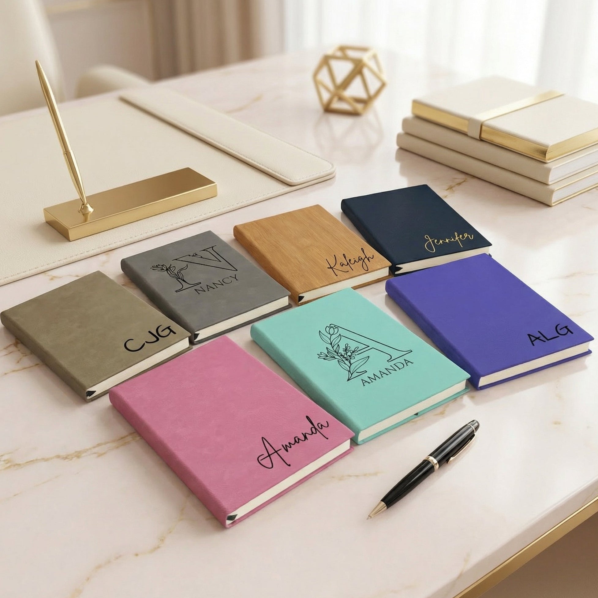 Set of personalized notebooks on a marble surface with a pen.