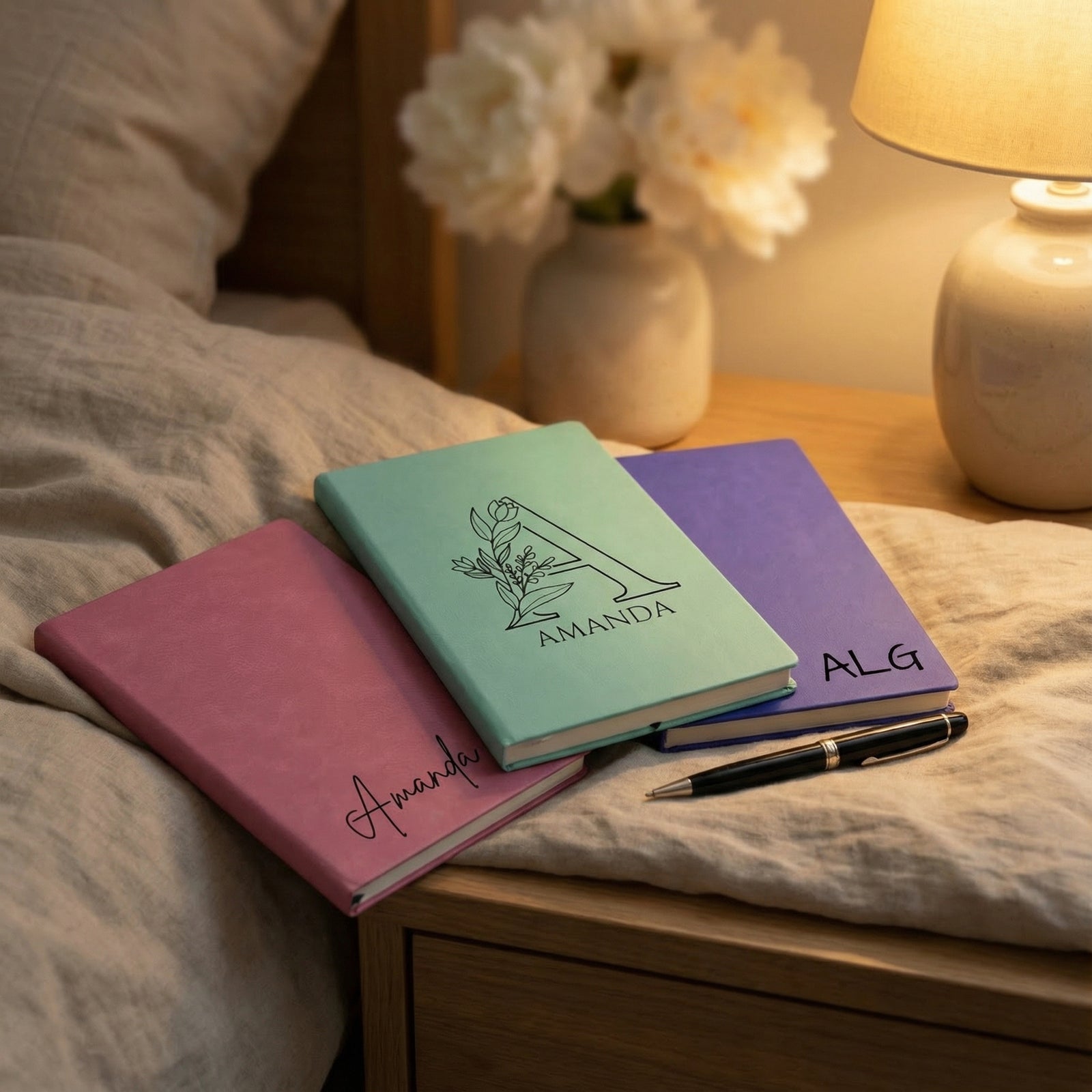 Set of personalized notebooks on a marble surface with a pen.