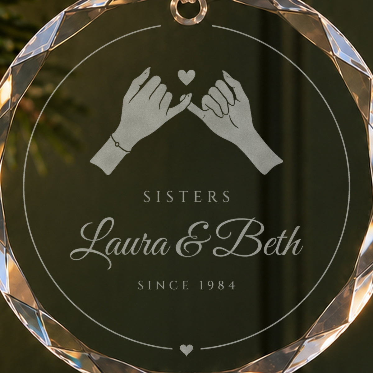 Close-up of the frosted pinky promise engraving on the sister Christmas ornament, with Sisters, Laura & Beth and Since 1984